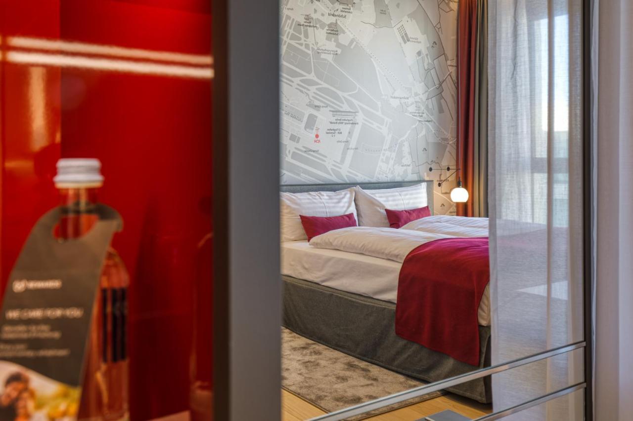 Intercityhotel Berlin Airport Ber Terminal 1 & 2 Schoenefeld Ngoại thất bức ảnh The photo shows a modern hotel room that features a comfortable bed with white linens and a red accent blanket. Behind the bed is a stylish wall displaying a map design. The room has large windows dressed with light-colored curtains, allowing natural